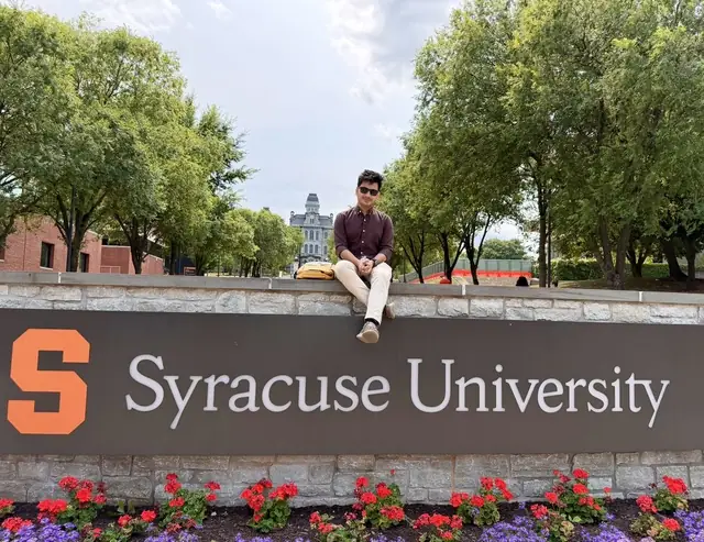 Naim Bin Hasan on the Syracuse University sign at the start of his fully funded PhD in Information Science and Technology.